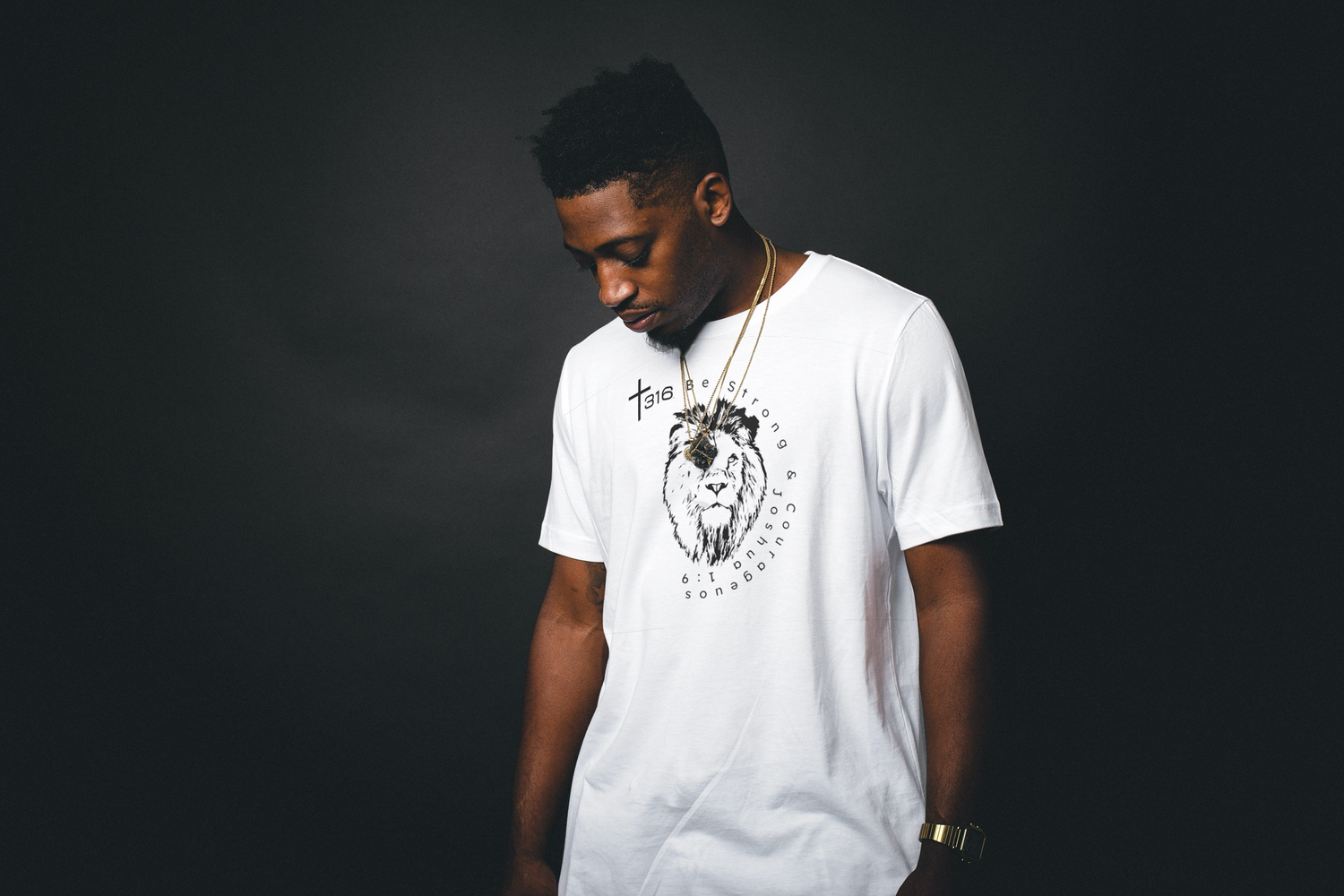 An African American man in a T-shirt sits on a window ledge, wearing a white hoodie, lost in contemplation.