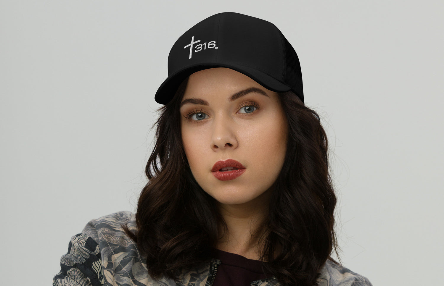 A woman in a black trucker hat featuring the word faith prominently displayed on the front.