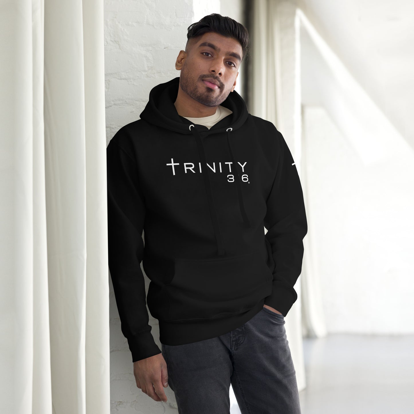 A man models a unisex premium black hoodie, showcasing its stylish design and comfortable fit.