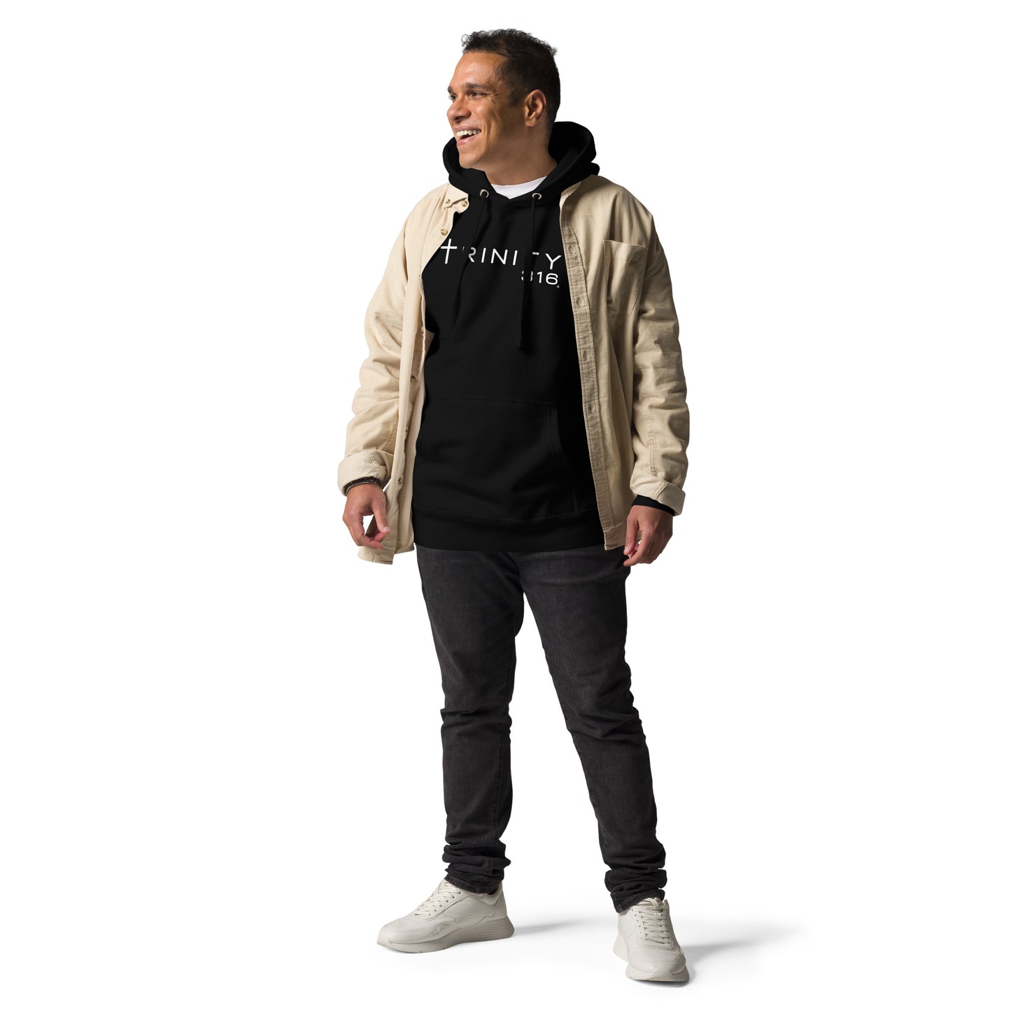 A man in a black unisex premium hoodie and jeans poses confidently for a photo, showcasing a casual style.