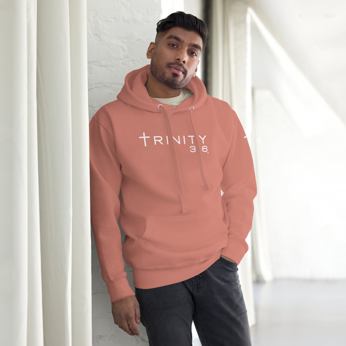 A man in a dusty rose unisex premium hoodie featuring the word trinity 316 prominently displayed on the front.