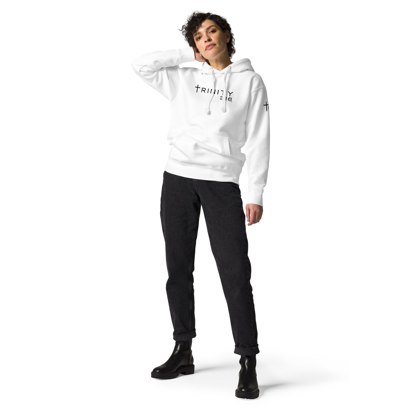 A woman in a white unisex premium hoodie and black pants stands confidently, showcasing a casual yet stylish look.