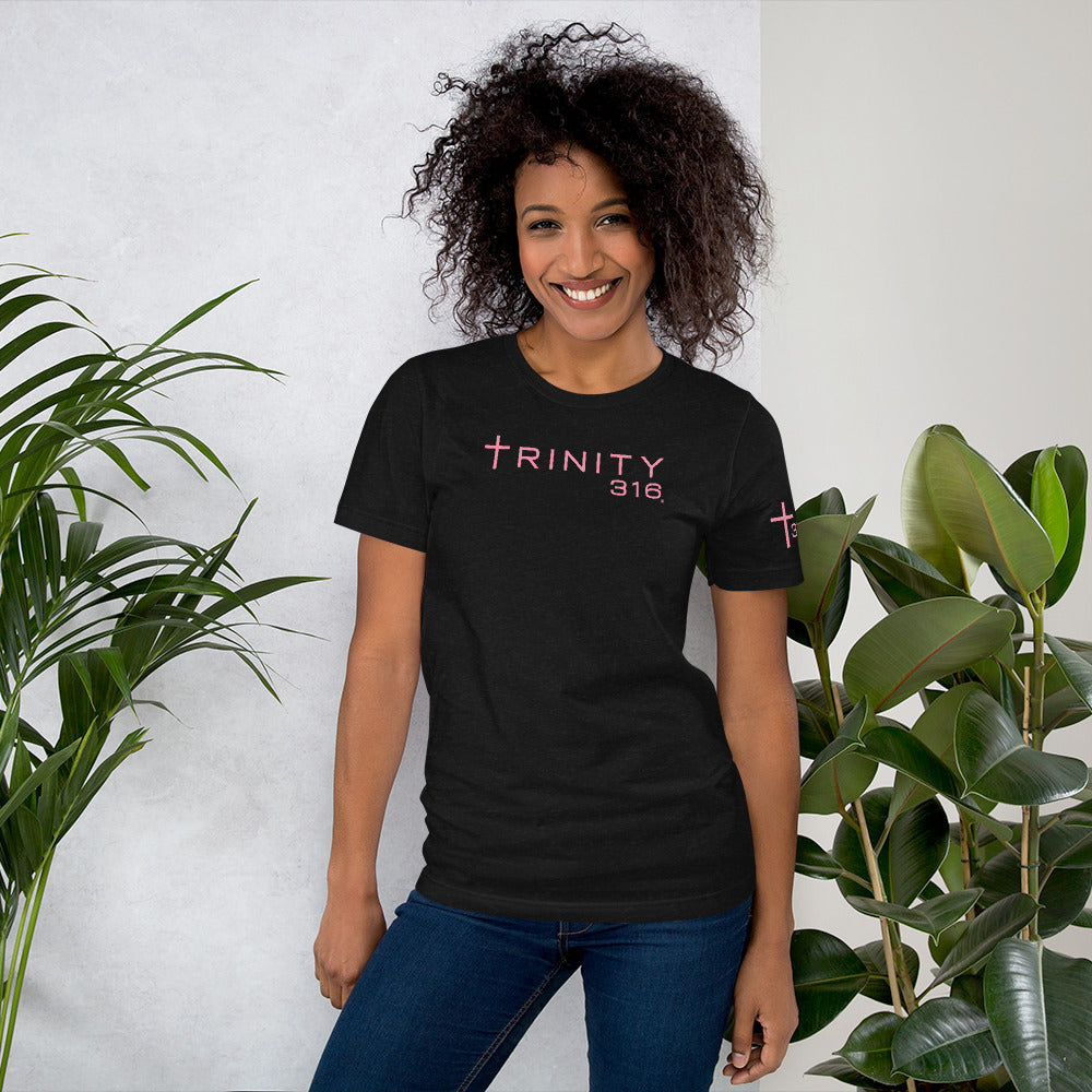 A woman models a unisex staple t-shirt in black heather, featuring the Trinity Club logo prominently on the front.
