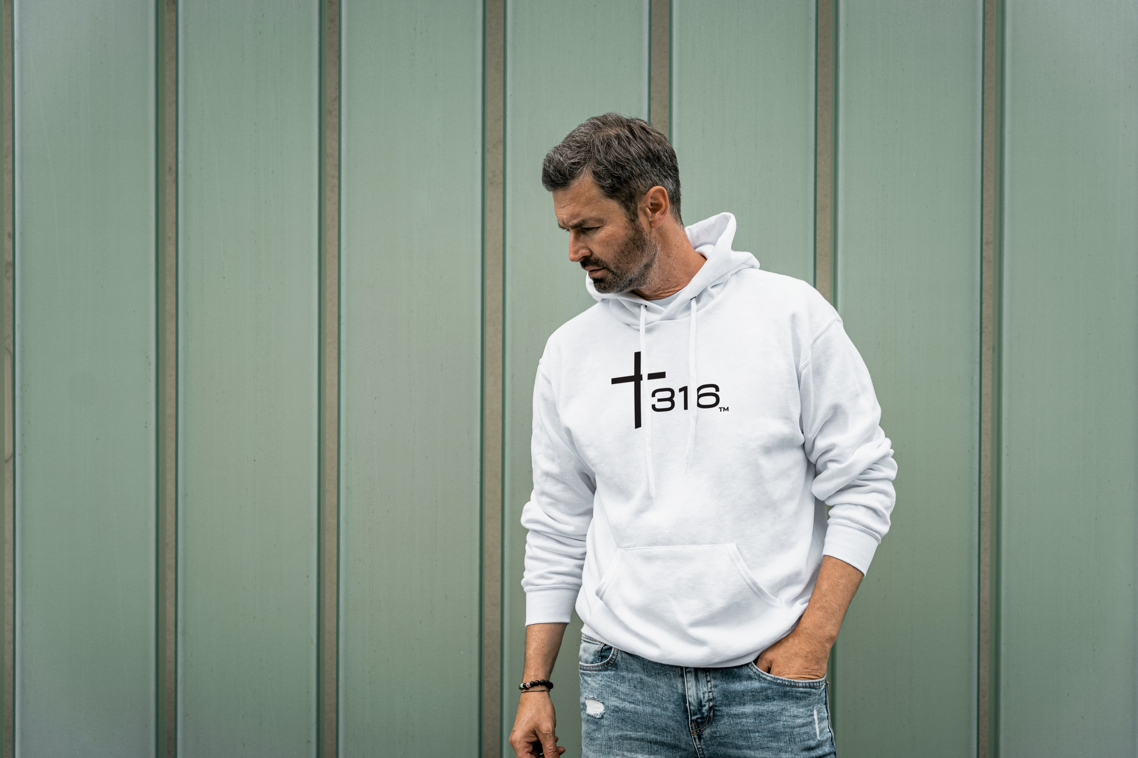 A man in a white t-shirt featuring a cross, embodying the spirit of faith and style